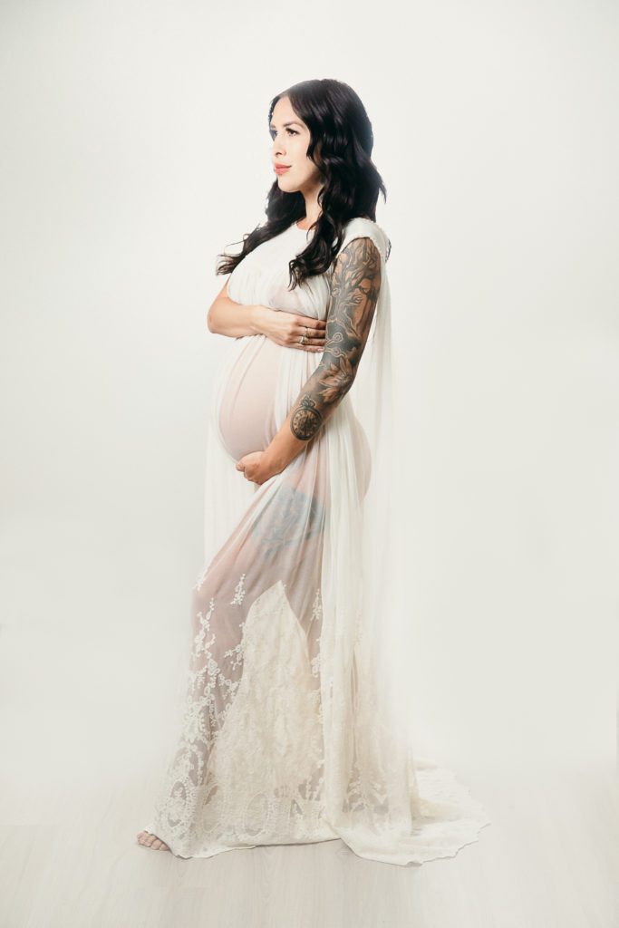 Pregnant tattooed mama wearing a sheer lace dress for her pregnancy photoshoot orange county.
