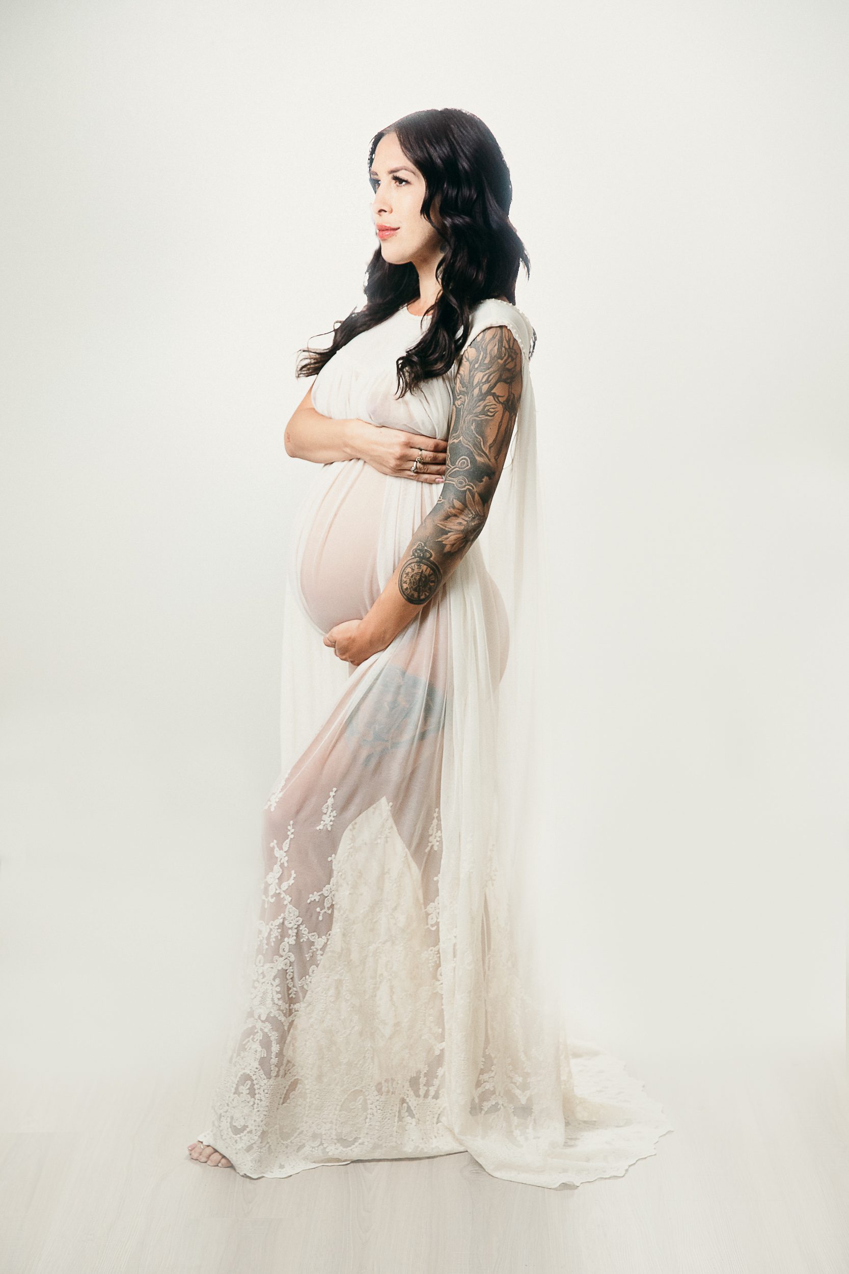 Pregnant tattooed mama wearing a sheer lace dress for her maternity photoshoot orange county.