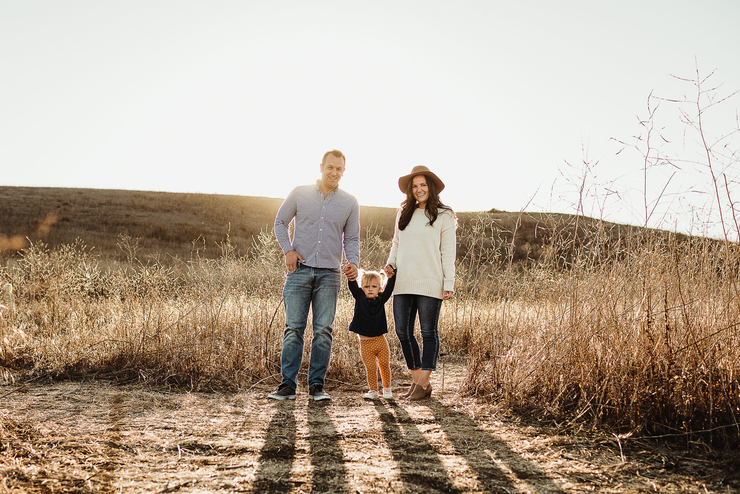Family of three standing in a dry field in orange county