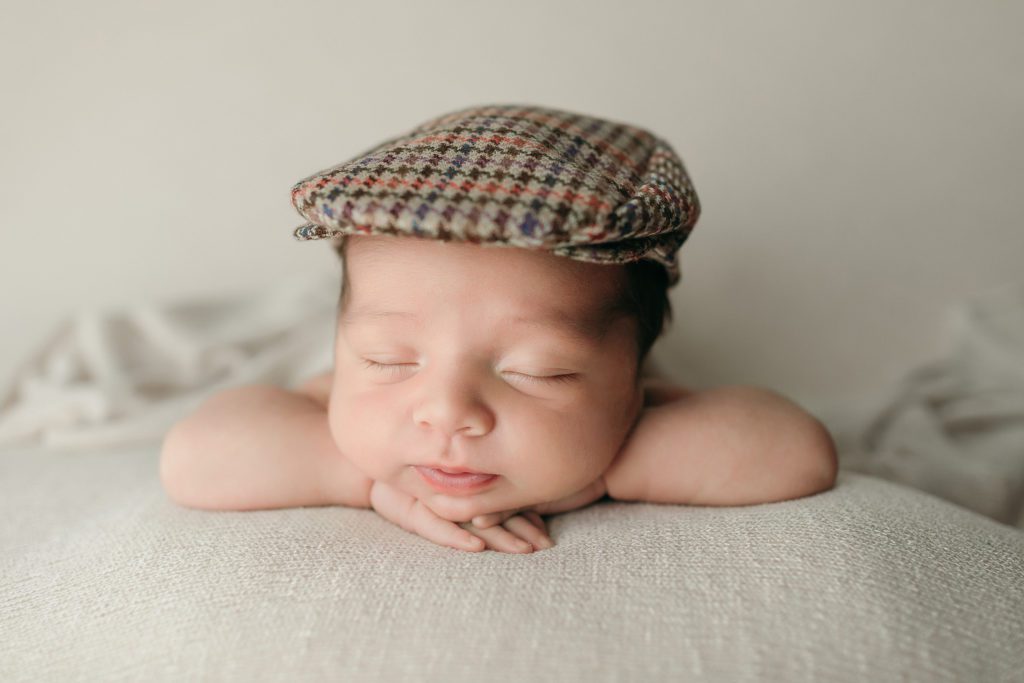 Newborn baby boy photoshoot wearing a newsboy hat