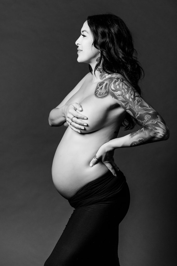 Black and white image of a pregnant woman topless posing for her maternity photoshoot orange county.

