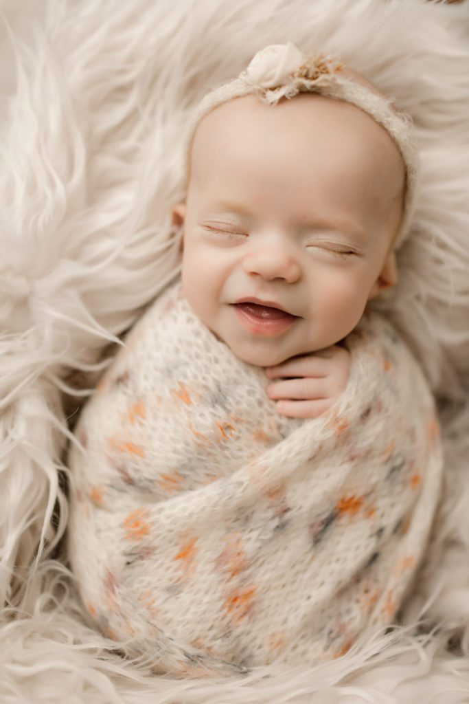 Newborn baby wrapped up in a bundle and smiling.